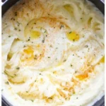 Creamy mashed potatoes recipe in a bowl garnished with herbs