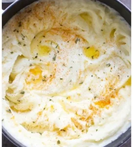 Creamy mashed potatoes recipe in a bowl garnished with herbs