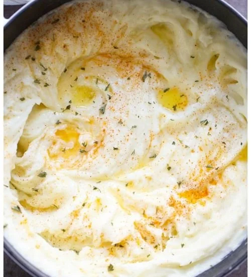 Creamy mashed potatoes recipe in a bowl garnished with herbs
