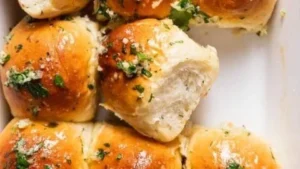 Freshly baked garlic bread rolls with herbs and cheese on a wooden table